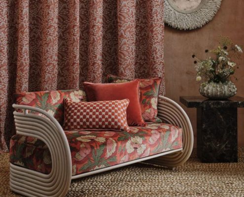 A braided jute rug beneath a sofa with red cushions