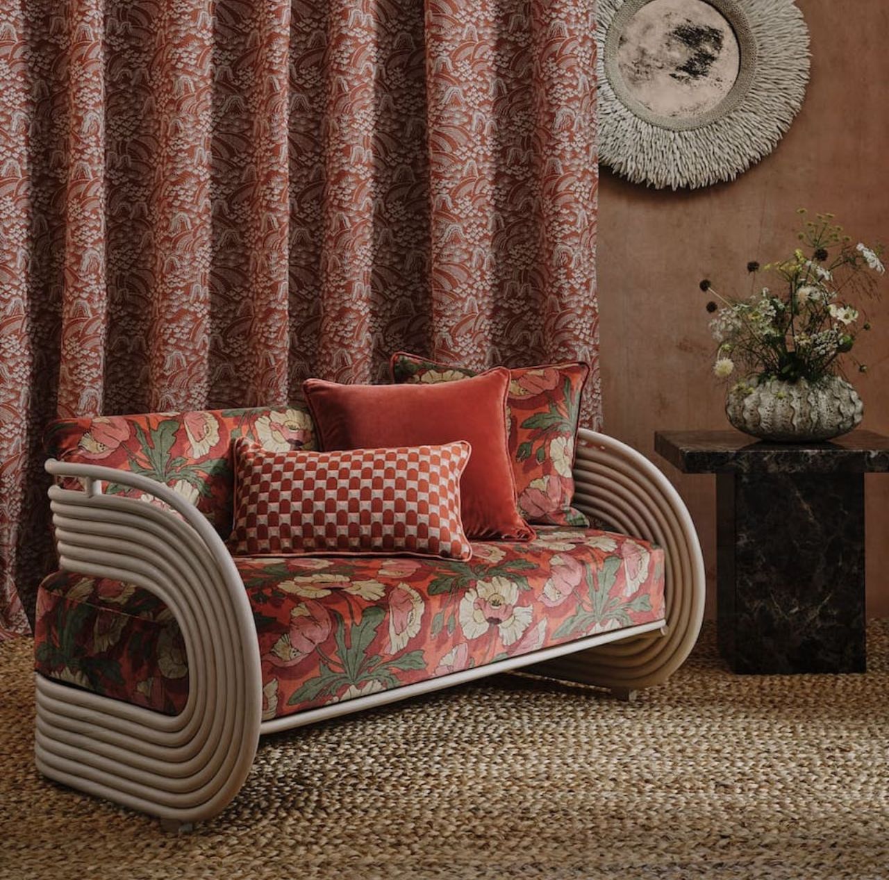 A braided jute rug beneath a sofa with red cushions